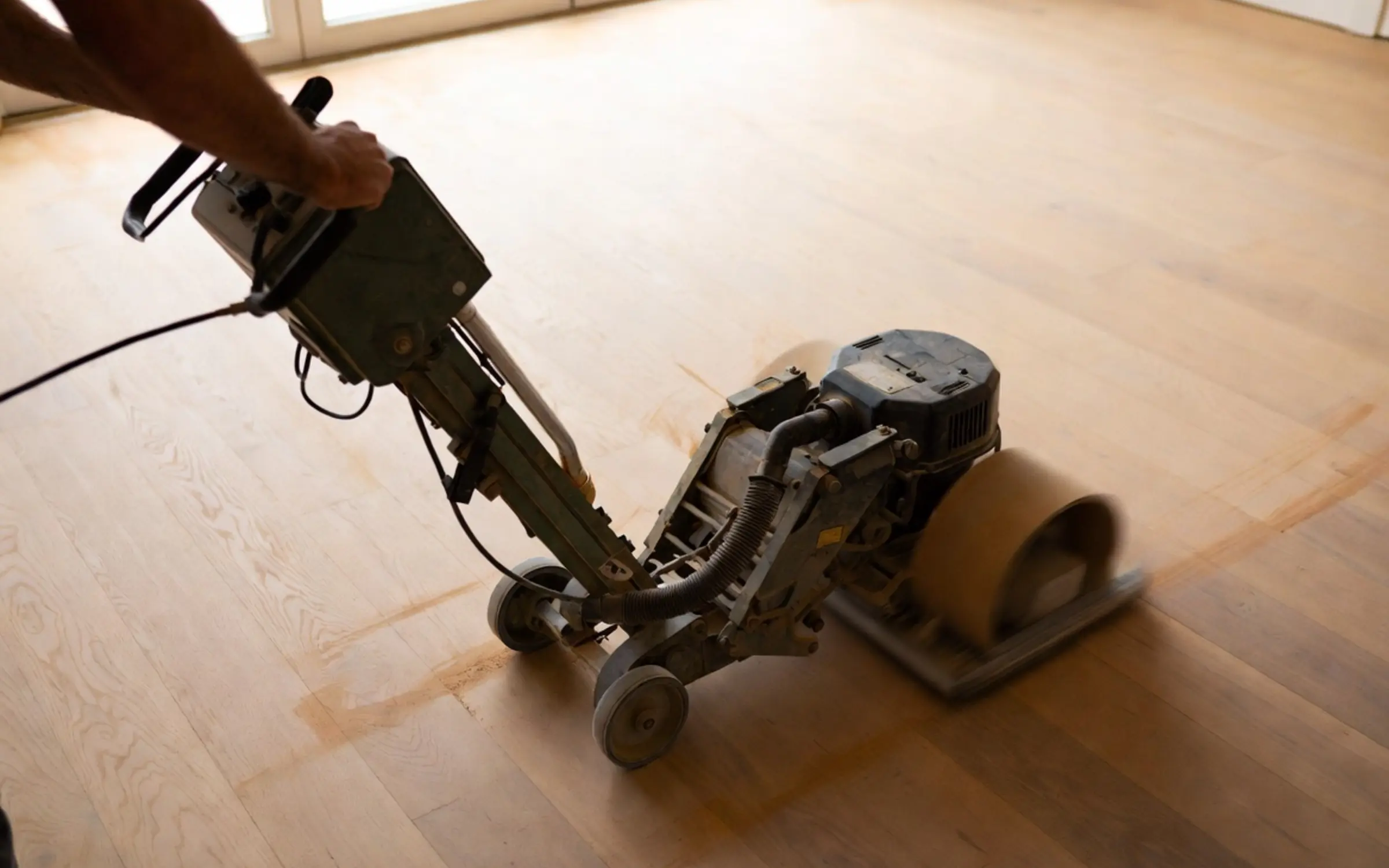 Craftsman operating a drum floor sander on a Toronto hardwood floor