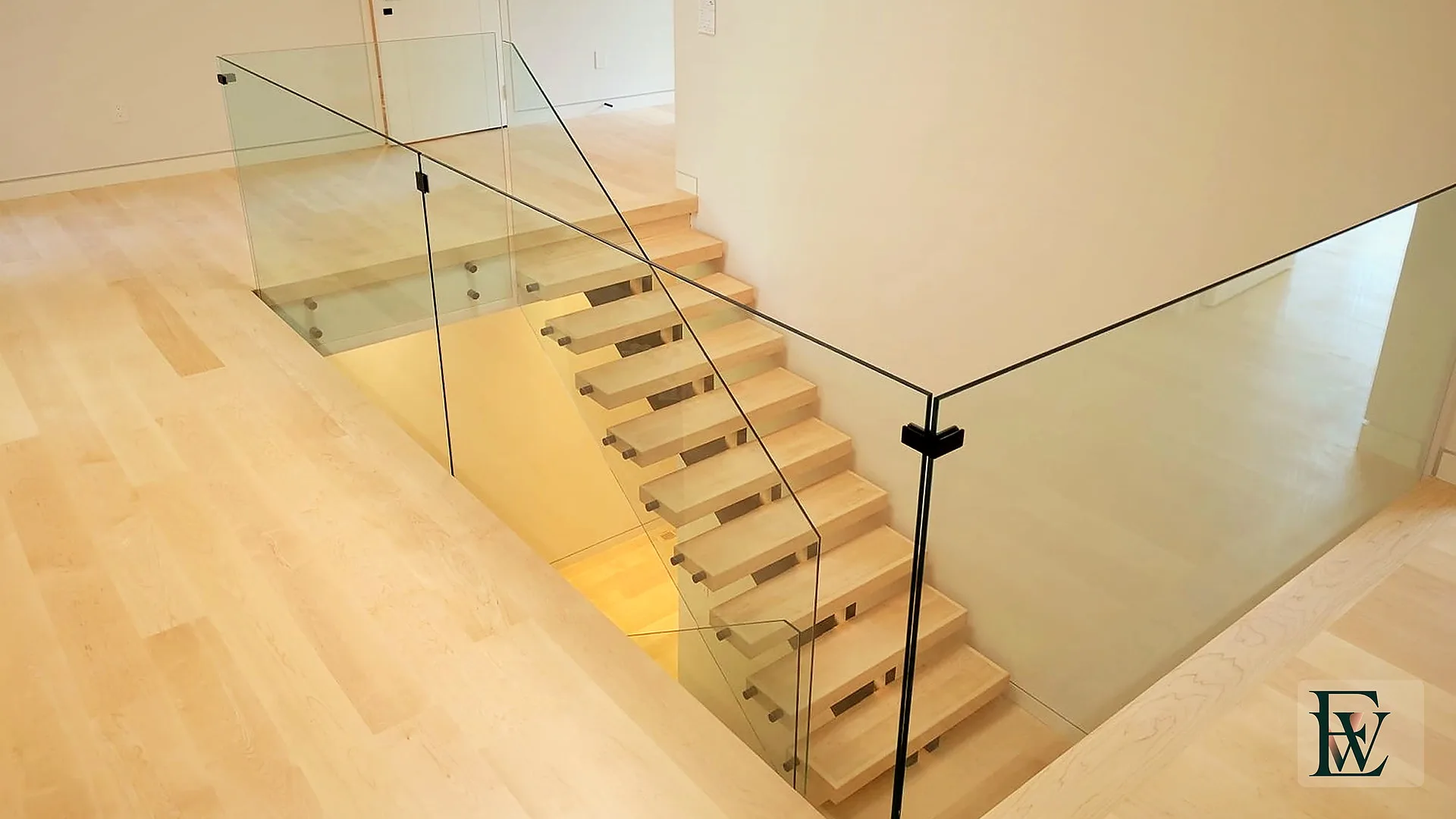 Frameless glass return and maple nosing at the upper-floor stair opening.