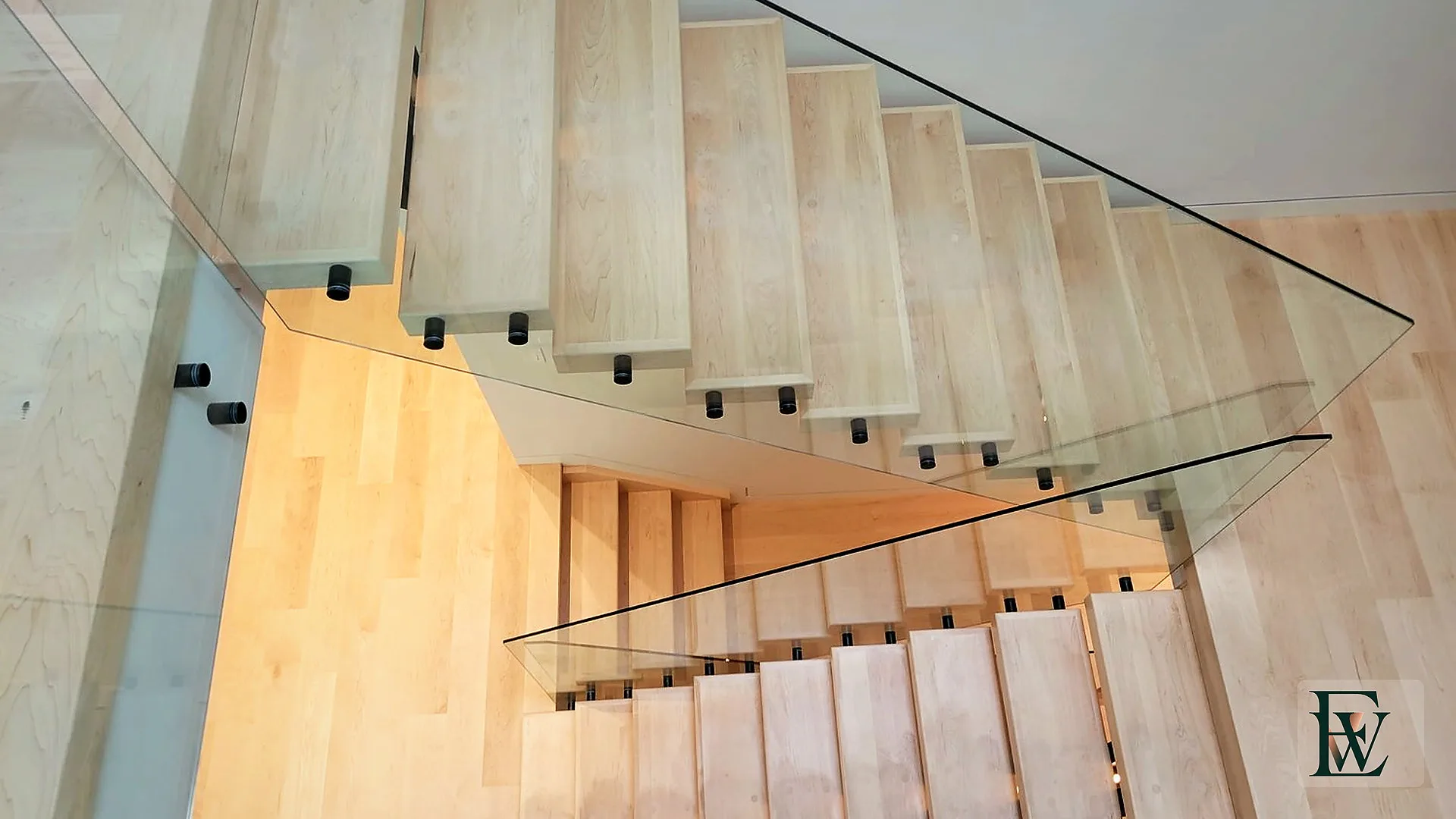 Looking up at hard maple open-riser treads through glass, showing fastener rhythm and grain match.
