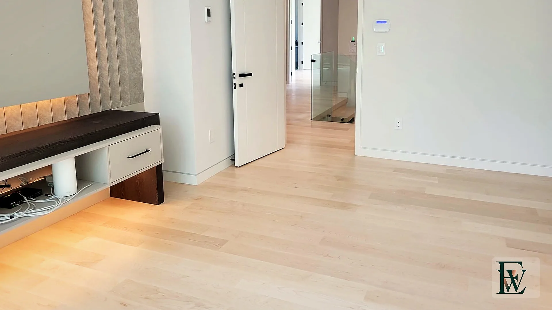 Light hard maple flowing from the bedroom through a white door into the upper hallway.
