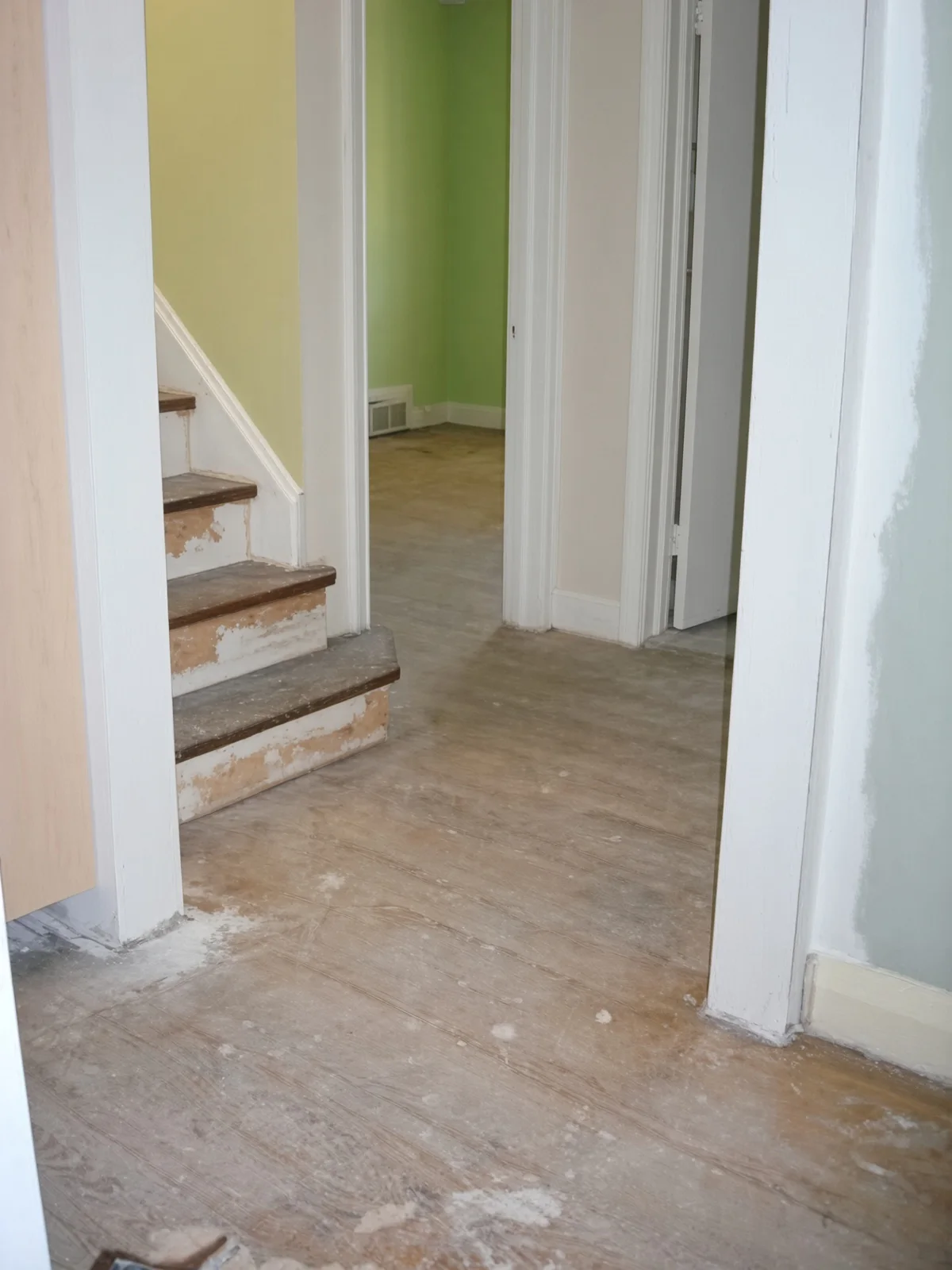 The stair and adjoining hall before work begins, dust and wear visible on both.