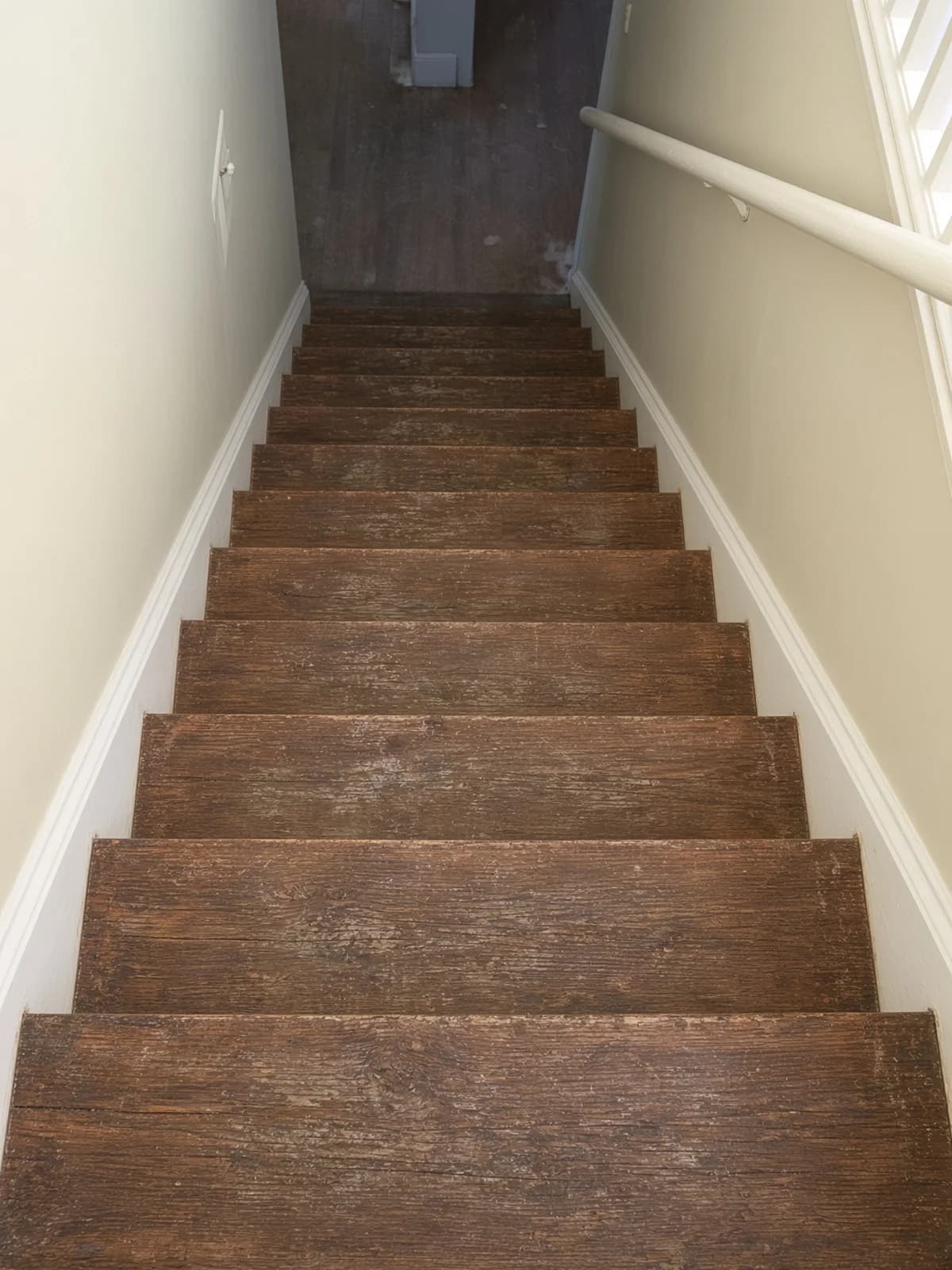 Looking down a worn stair run, traffic compressed into the grain of each tread.