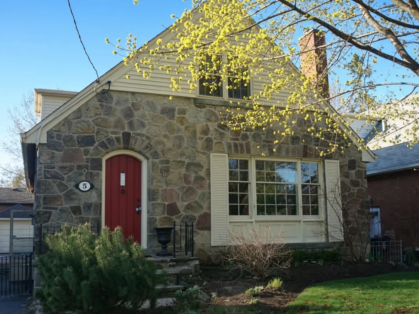 A stone cottage exterior with a red door — the heritage envelope the refinish sits inside.