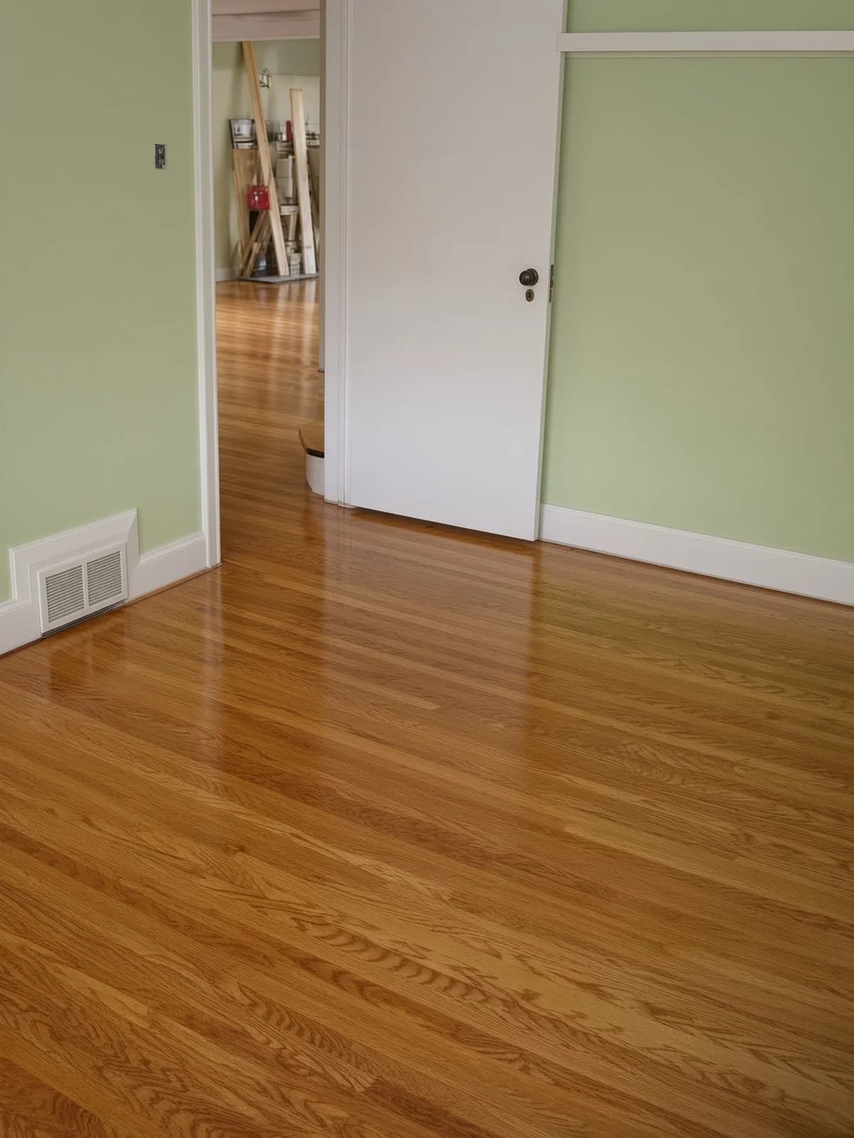One finished floor seen through a doorway into a second room, the surface reading as a single line.