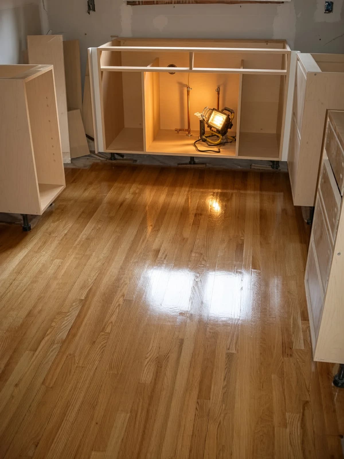 Raw cabinet boxes set on a floor that was finished before the kitchen trades arrived.